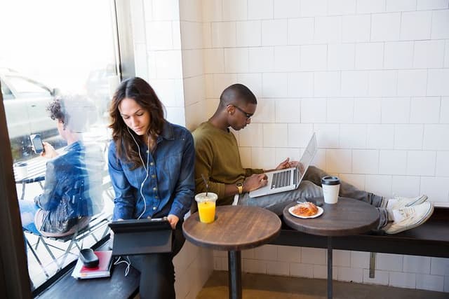To personer sidder på en cafe og arbejder på deres bærbare computere