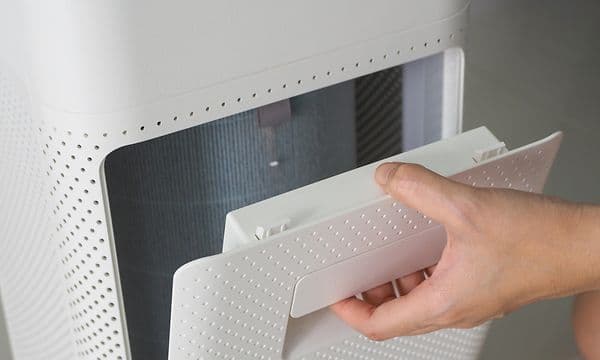 En hånd som skal skifte pollenfilter på en luftrenser