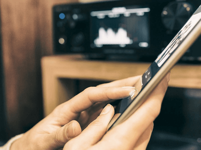 Person styrer lyden på tablet - medieafspiller i baggrunden