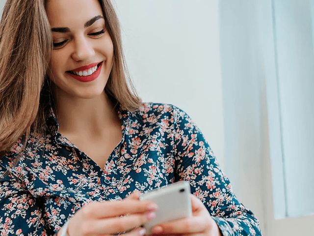 Smilende kvinde kigger på smartphone