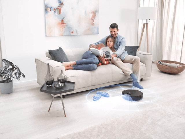 Ecovacs Deebot T9 AIVI gulv rengøres, mens mand og kvinde slapper af på sofaen