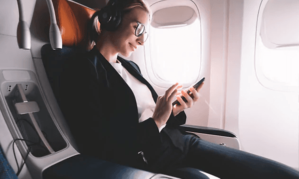 kvinne slapper av på fly med støykansellerende hodetelefoner
