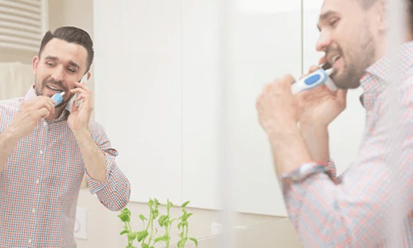  Elektrisk tandbørste - en mand, der børster tænder i et badeværelseman  brushing his teeth in a bathroom