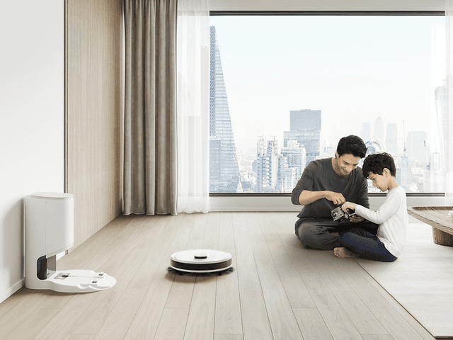 Ecovacs DEEBOT-N8 pluss en mann og en gutt som sitter på et gulv foran et stort vindu