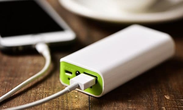 Powerbank oplader en smartphone på et cafébord ved siden af en kaffekop