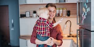 Man holding little boy in front of a stainless fridge