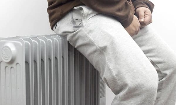 Person læner sig op af olieradiator