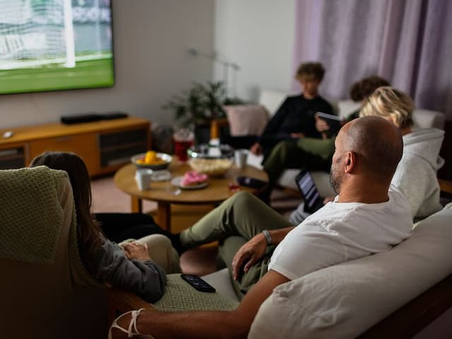 Familie i sofa ser på sport på TV