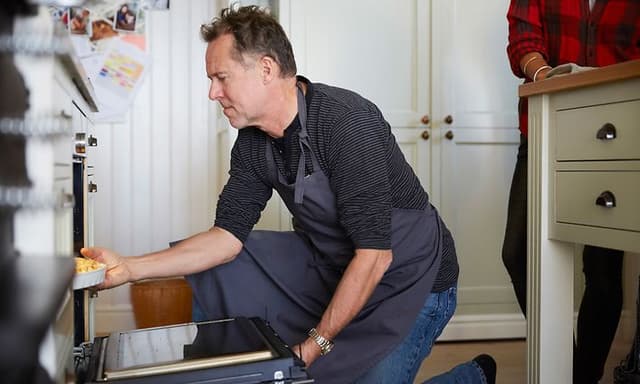Mann som tar ut mat fra stekeovnen
