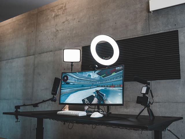 Streamingoppsett for gaming på et skrivebord med monitor, ringlys og webkamera