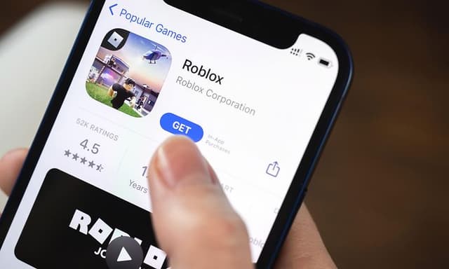 En hånd som holder en telefon som installerer Roblox fra App Store