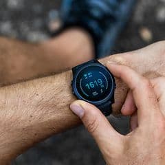 en mann sjekker smartklokke på håndledd