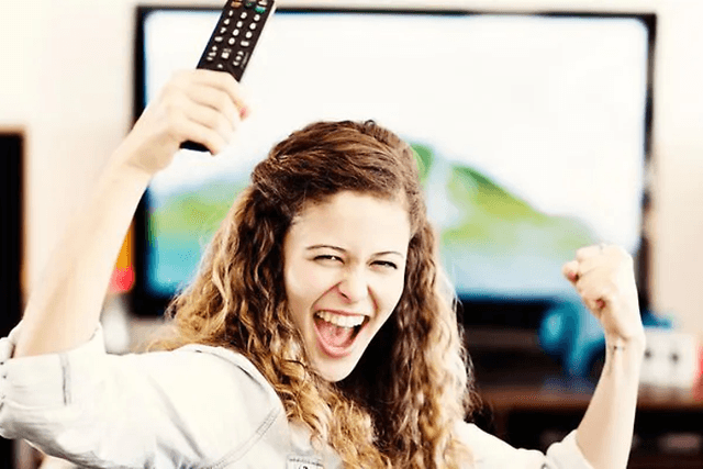 Jublende kvinde foran TV