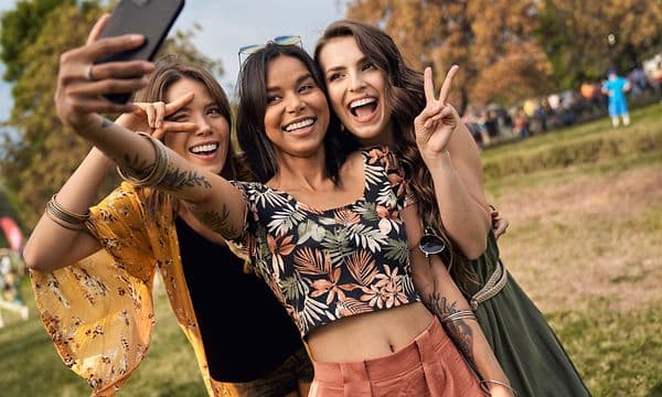 tre jenter tar selfie sammen med en smarttelefon