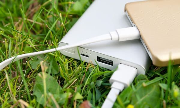en nødlader lader en smarttelefon liggende på gress