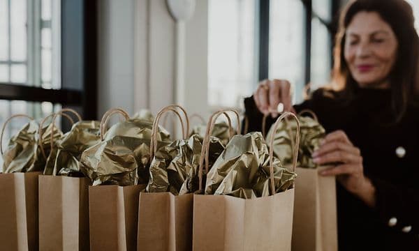 Kvinne forbereder gaveposer som er satt i to rader på et bord