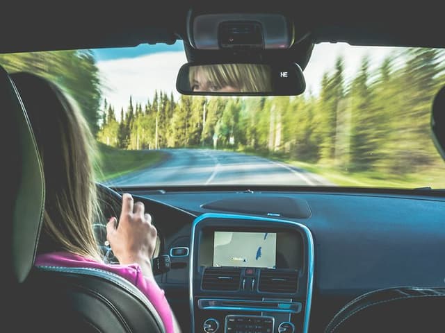En kvinde, der kører bil med GPS-navigationen sat til