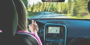 kvinne kjører bil med GPS på