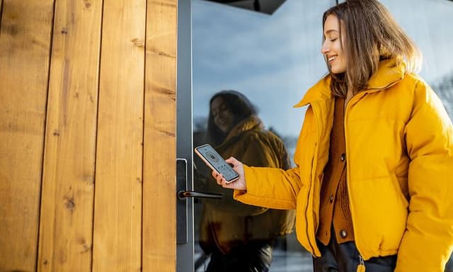 en kvinne låser en smart lås på utgangsdør med smarttelefon