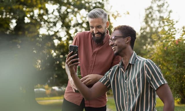 To mænd kigger på en telefon i en have