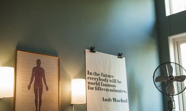 mor og barn leser i seng med en vifte i bakgrunnen