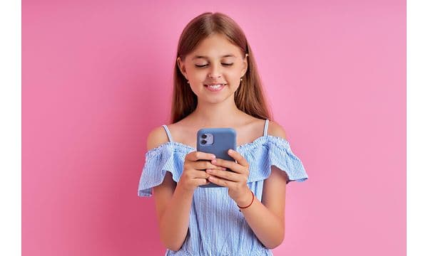 en liten jente holder en mobiltelefon med silikondeksel på