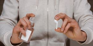 mann holder rengjøringsspray og en airpod