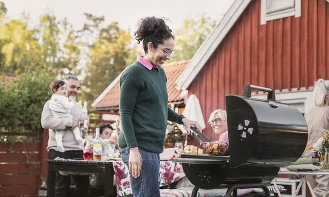 kvinne står og griller med mennesker i bakgrunnen