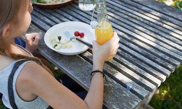 en jente holder en flaske saft ved et bord i en hage