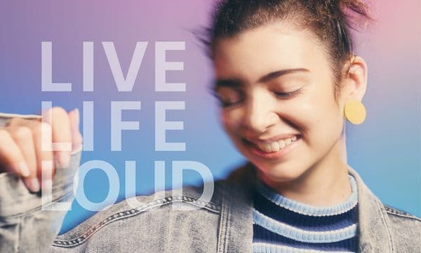 Ofokuserad bild med glad kvinna som verkar dansa och texten "live life loud" 