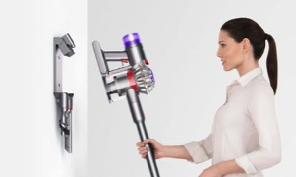 En kvinne som plasserer Dyson V8 i den veggmonterte dokkingstasjonen