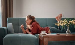 Girl laying on a couch using a laptop
