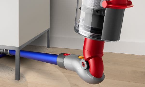 Lähikuva Dyson V10 -pölynimurin tapuisasta adapterista imuroimassa huonekalun alta