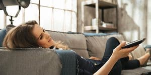 Relaxed woman lying on sofa and watching tv