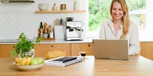 En kvinde sidder i sit køkken og arbejder på sin laptop