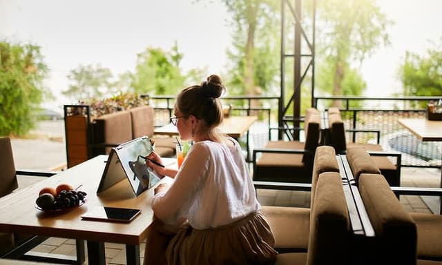 Kvinde, der sidder udenfor og arbejder på en tablet