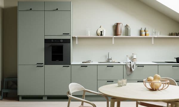 Loftkök i serien EPOQ Trend Sage med vit bänkskiva, integrerad ugn, runt matbord och svarta handtag.