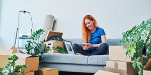 en ung kvinne sitter i en sofa med flytteesker rundt seg