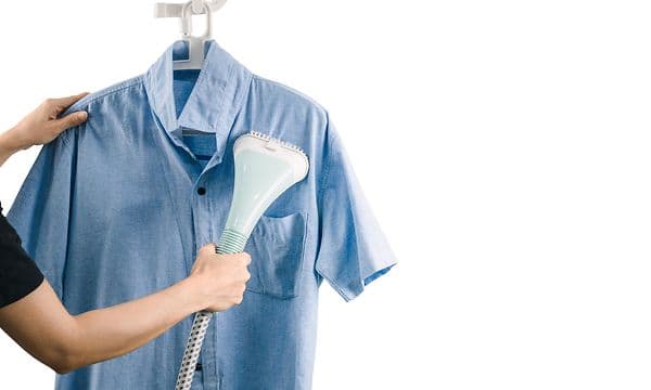 person steamer en blå skjorte med en tøydamper