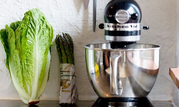 kjøkkenmaskin fra Kitchenaid og flere kokkekniver på en vegg over en kjøkkenbenk