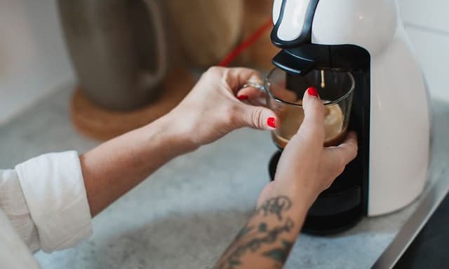 kvinne lager kaffe på kaffemaskin