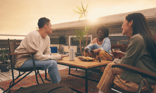 Sony-højttaler på terrassebord og tre unge mennesker omkring