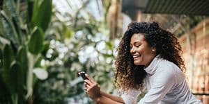Smilende kvinne på balkong som ser på smarttelefon
