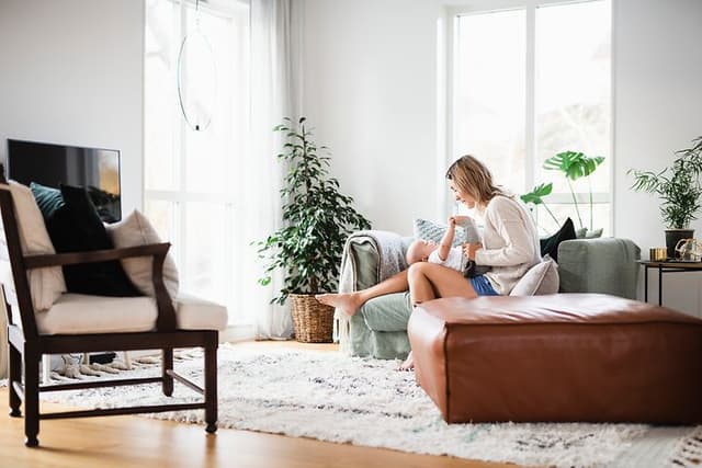Nainen vauva sylissään istuu valoisassa olohuoneessa