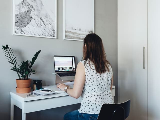 Kvinne jobber på laptop på lite hjemmekontor
