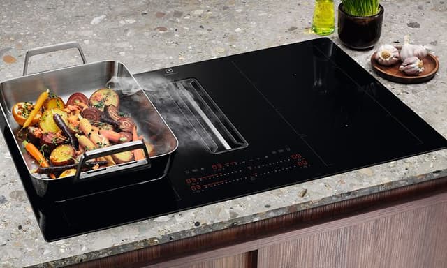 Grønnsaker tilberedes på to koblende kokeplater på en Electrolux koketopp med ventilator ved hjelp av brofunksjonen