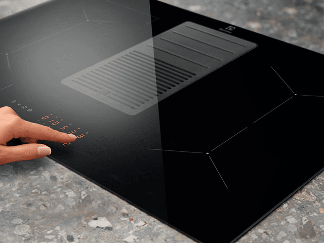 Närbild av ett finger som trycker på touchscreen på en spishäll