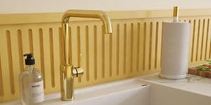 Epoq Trend Mellow gult kjøkken med marmormønstret laminatbenkeplate, stor hvit vask og blandebatteri i messing