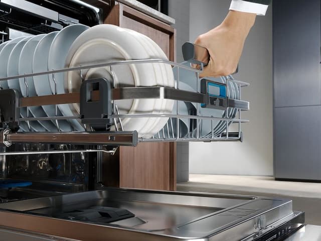 Manden tager tallerkener ud af en integreret Electrolux opvaskemaskine