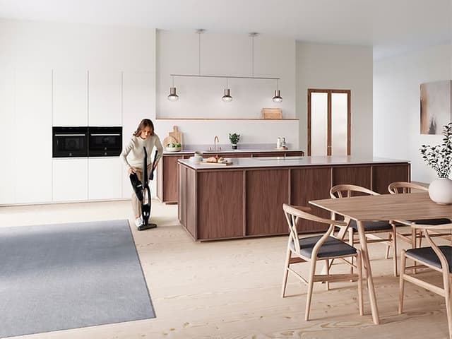 Kvinde rengør køkken med en støvsuger fra Electrolux